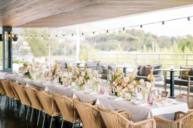 Büyük bir restoran terasında hasır sandalyeli uzun festival masası. Yüksek kalite fotoğraf