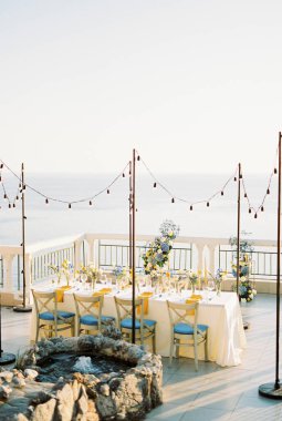 Denize bakan terasta çiçekli şölen masası duruyor. Yüksek kalite fotoğraf