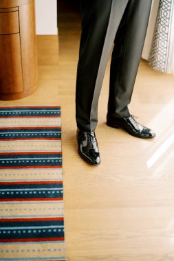 Takım elbiseli damat bir otel odasının ahşap zemininde duruyor. Kırpılmış. Yüzsüz. Yüksek kalite fotoğraf