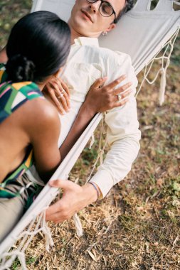 Adam yeşil bahçedeki bir hamakta yatan kadına bakıyor. Yüksek kalite fotoğraf