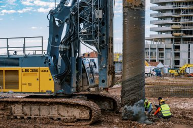 İşçiler yere kazık döşeyen bir sondaj makinesinin yanında oturuyorlar. Yüksek kalite fotoğraf