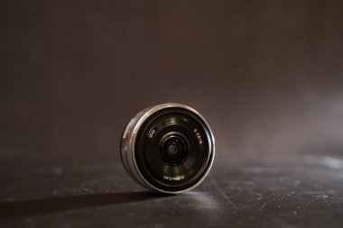 Sony A6500 kamerasının yedek lensi siyah bir masanın üzerinde duruyor. Yüksek kalite fotoğraf