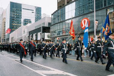 Canlı bir şehir geçidi çeşitli yürüyüş birlikleri ve renkli bayraklar sergiliyor.