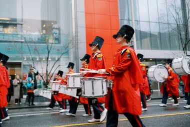 Canlı ve renkli bir yürüyüş bandosu şehrin caddesinde enerjik bir performans sergiliyor.