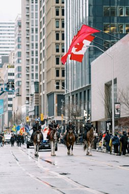 Şehirde görkemli atlar ve büyük bir Kanada bayrağı olan canlı bir geçit töreni.