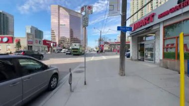 Modern mimari ve mağazaların yer aldığı hareketli şehir sokak sahnesi.