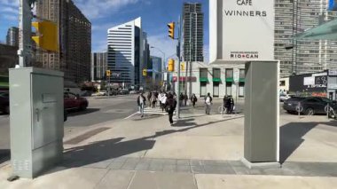 Arka planda yayalar ve modern binaların olduğu işlek bir sokak manzarası