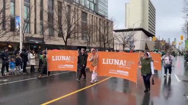 Çeşitli LiUNA afişlerinin yer aldığı canlı ve canlı bir işçi geçidine ait sahneler