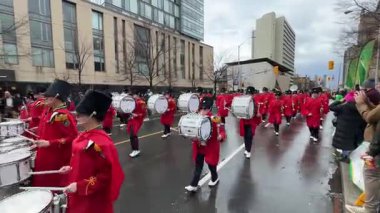 Kırmızı üniformalı bir bando bandosunun eğlendirip kutladığı canlı bir geçit töreni.