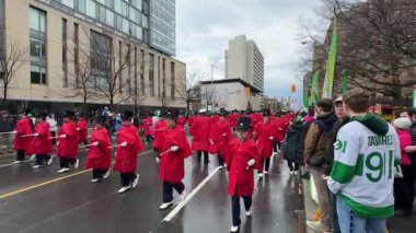 Parlak kırmızı üniformalı canlı bir bando geçit töreninde gösteri yapıyor.