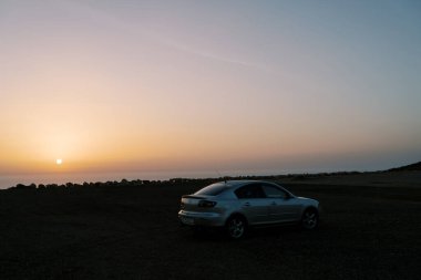 Gün batımında araba deniz kıyısında duruyor. Yüksek kalite fotoğraf
