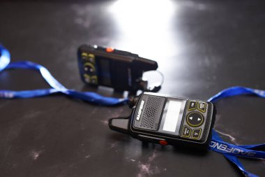 Bir çift küçük Baofeng BF-T1 telsizi mavi kurdeleli siyah bir masanın üzerinde yatıyor. Yüksek kalite fotoğraf