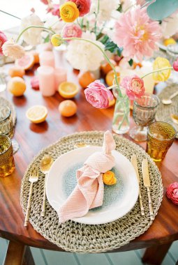 Düğümlenmiş peçete, şenlik masasındaki hasır bir halıda bir tabakta yatıyor. Yüksek kalite fotoğraf