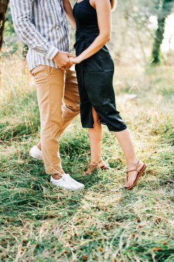 Erkek ve kadın yeşil bir korulukta el ele tutuşuyorlar. Kırpılmış. Yüzsüz. Yüksek kalite fotoğraf