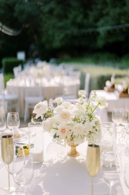 Bir buket çiçek, bardaklar ve bronz kadehlerin arasında bir setin üzerinde duruyor. Yüksek kalite fotoğraf