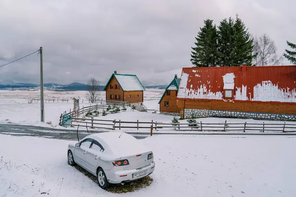 Karla kaplı araba yol kenarında, ahşap kulübelerin önünde duruyor. Yüksek kalite fotoğraf