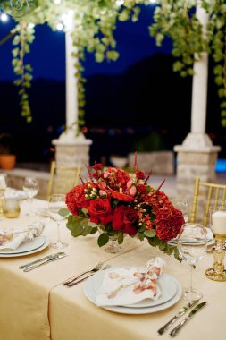 Kırmızı çiçek buketi, avluda sütunları olan bir şenlik masasında duruyor. Yüksek kalite fotoğraf