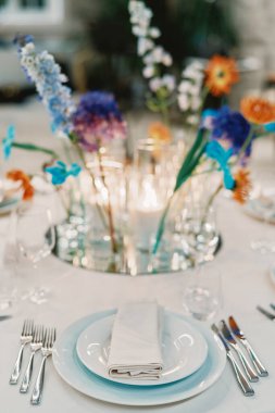 Katlanmış peçete ve çatal bıçaklı tabaklar bir buket çiçeğin yanındaki masanın üzerinde. Yüksek kalite fotoğraf