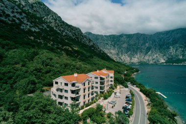 Arabalar, dağların eteğindeki deniz kıyısındaki modern otellerin yakınına park edilmiştir. Karadağ. Drone. Yüksek kalite fotoğraf