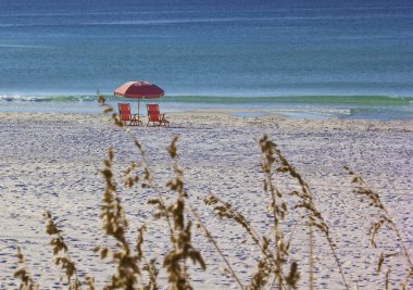 Destin Beach, Florida 'da boş pembe plaj sandalyeleri ve şemsiye.