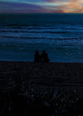 Miami, Florida 'daki Atlantik Okyanusu üzerinde gün batımına hayran olan bir çiftin silueti.