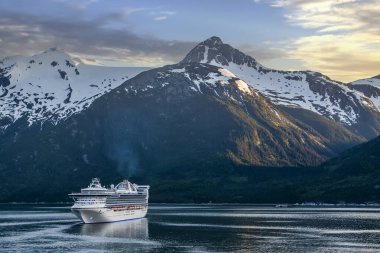 Alaska dağlarının tepesinde akşam gökyüzü, İç Geçitte tekneler.