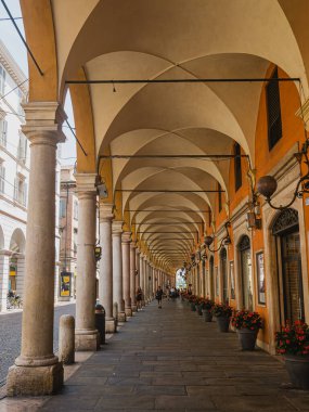 MODENA, İtalya - 22 Haziran 2023: İnsanlar Modena 'nın tarihi merkezinde sıcak bir yaz gününde tipik bir porticonun altında yürürler