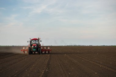 Traktör tohumu olan çiftçi - ilkbaharda tarım tarlalarına ekin ekiyor.