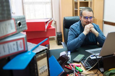 Ofisteki iş yükü ve iş baskısı yüzünden başı ağrıyan bir kamu şirketinde çalışan bir idari işçi. Yorgunluk, kaos ve son teslim tarihinden muzdarip endişeli bir adam..