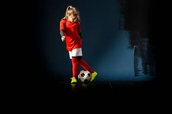 An elementary school girl is playing indoor soccer