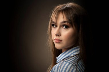 Young woman looking at camera isolated on dark background. A beautiful female portrait.