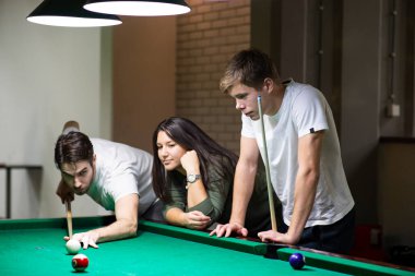 Bilardo oynayan bir grup neşeli genç arkadaş.
