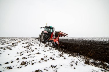 Traktör tarlada çalışıyor, kışın toprağı bahar ekimi için hazırlıyor. Tarıma elverişli toprakların yetiştirilmesi.