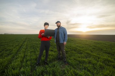 Bir kadın tarım uzmanı ve genç bir çiftçi baharda genç buğday ektiler.