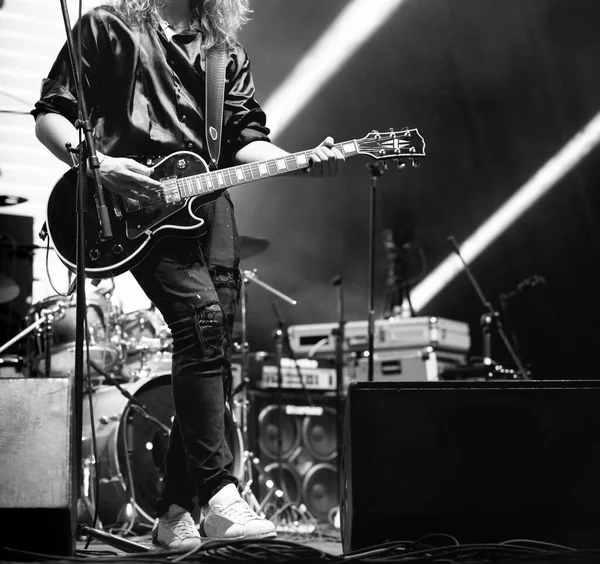 Sahnede uzun saçlı bir gitarist rock konserinde bas gitar çalıyor. 