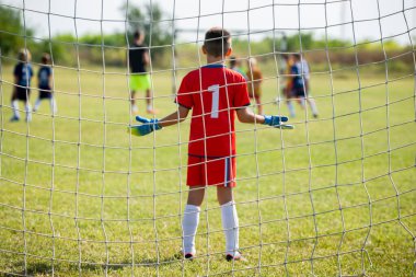 Spor stadyumunda futbol takımı yarışması. Futbol kalesi ve kaleci ön planda.