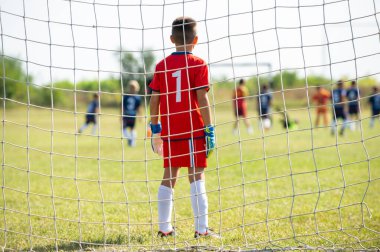 Spor stadyumunda futbol takımı yarışması. Futbol kalesi ve kaleci ön planda.
