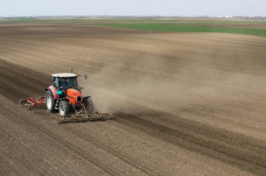 Traktör tarlada çalışıyor, tarlayı ekime hazırlıyor, tarlayı sürüyor.