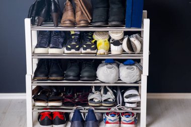 Ayakkabı rafındaki bir ailenin farklı ayakkabı ve spor ayakkabıları koleksiyonu. İç dizaynında raflar olan gardırop 