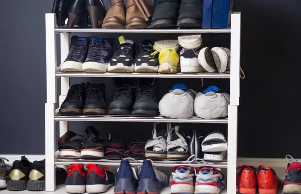 A collection of different shoes and sneakers of one family in a shoe rack. Wardrobe with shelves in home interior design