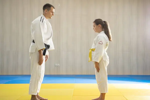 Judo master and young yellow belt judo girl in white judogi