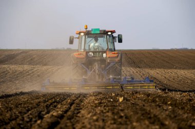 Traktör tarlada çalışıyor, tarlayı ekime hazırlıyor, tarlayı sürüyor.