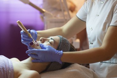 Spa, tatil köyü, güzellik ve sağlık konsepti. Güzellik salonunda yüz bakımı gören güzel bir kadın. Yüz bakımı. Kozmetoloji 