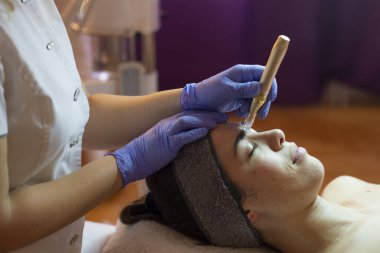 Spa, tatil köyü, güzellik ve sağlık konsepti. Güzellik salonunda yüz bakımı gören güzel bir kadın. Yüz bakımı. Kozmetoloji 
