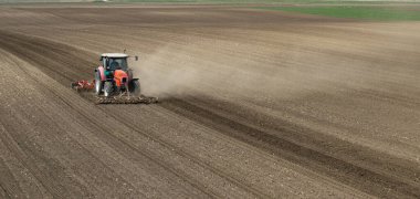 Traktör tarlada çalışıyor, tarlayı ekime hazırlıyor, tarlayı sürüyor.