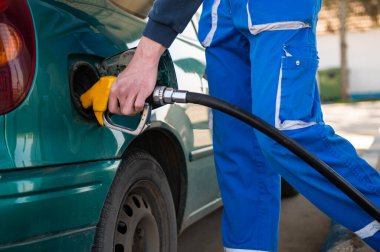 Makineyi yakıtla doldurmak için. Benzin istasyonu pompası. Benzin deposunu dolduran adam, elinde hortum tutuyordu.