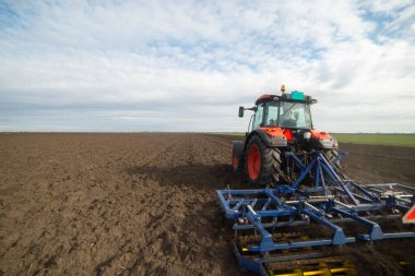 Traktör tarlada çalışıyor, tarlayı ekime hazırlıyor, tarlayı sürüyor.