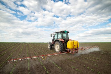 Tractor spraying pesticides at soy bean fields clipart