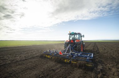 Traktör tarlada çalışıyor, tarlayı ekime hazırlıyor, tarlayı sürüyor.