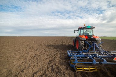 Traktör tarlada çalışıyor, tarlayı ekime hazırlıyor, tarlayı sürüyor.